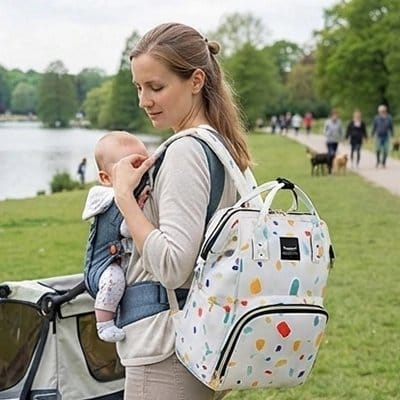 Maman bébé au parc avec sac à dos à langer blanc