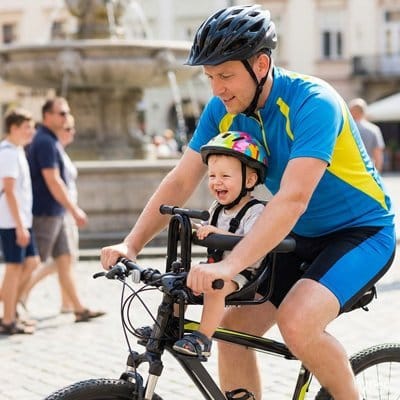 Papa en ville à vélo avec bébé dans PORTE BEBE VELO Confort Sécurisé