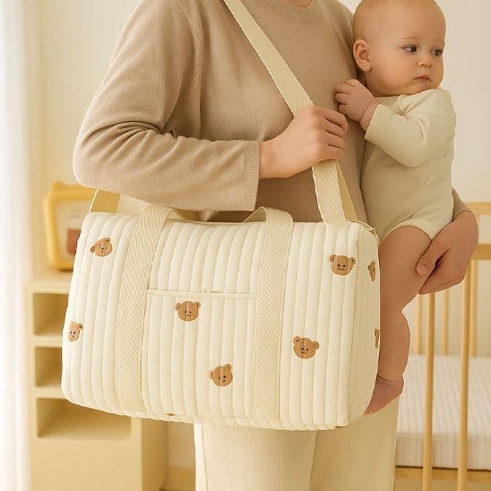 Maman avec bébé dans les bras et Sac a langer bebe beige avec motifs ourson a l'épaule