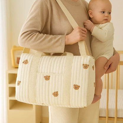 Maman avec bébé dans les bras et Sac a langer bebe beige avec motifs ourson a l'épaule